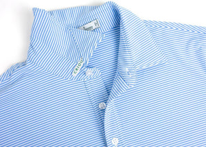 A man wears the CRIQUET Performance Sport Range Polo in Hobby Stripe - Bluebonnet, featuring light blue and white stripes, a collared neckline with three buttons, and lightweight, breathable fabric, standing against a plain white background.