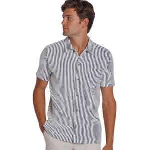 A man wears the CRIQUET Terrycloth Button Down Shirt in Striped Jacquard Natural—short-sleeved with vertical navy and white stripes and a chest pocket—paired with light pants for a breezy summer look.