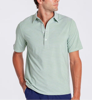A man in a CRIQUET PERFORMANCE SPORT RANGE POLO IN HOBBY STRIPE - GATOR walks on a golf course, wearing blue pants, a white cap and glove, holding a club and smiling. Trees and a golf cart are visible in the background.
