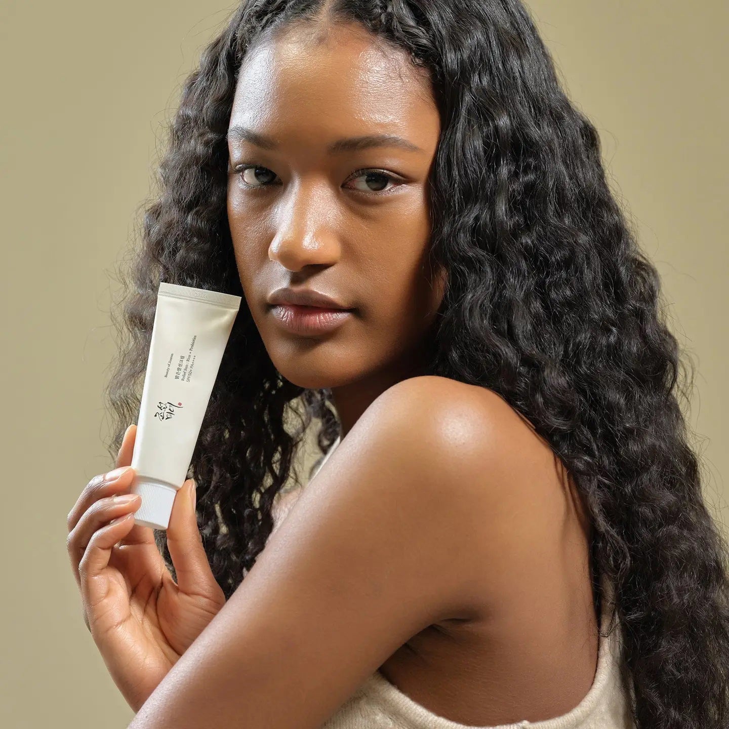 A white skincare tube with black text and red accents, featuring a secured cap, provides a minimalistic, elegant design. GLOWISS's BEAUTY OF JOSEON - RELIEF SUN RICE SPF50 offers lightweight sun protection. The background is plain white.