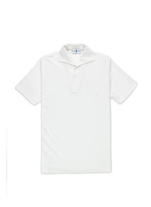 A man with light brown hair and a short beard wears the EDWARD ARMAH Pima Cotton Tailored Polo Shirt in dark blue and jeans, standing against a plain light background with a relaxed expression and one hand in his pocket.