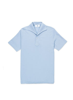 A man with light brown hair and a short beard wears the EDWARD ARMAH Pima Cotton Tailored Polo Shirt in dark blue and jeans, standing against a plain light background with a relaxed expression and one hand in his pocket.