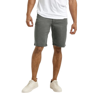 A person stands against a plain light background, wearing a white T-shirt, DUER No Sweat Relaxed Shorts in Gull made from stretch fabric, and white sneakers, with one hand in their pocket.
