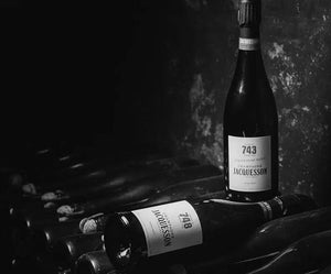 Two Champagne Jacquesson bottles labeled 743 and 748 resting on a cellar rack among other wine bottles at a Champagne & Caviar Dinner with Champagne Jacquesson.