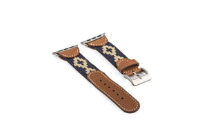 The LA MATERA - CORBINA Apple Watch Band in silver pairs artisan brown leather with a black fabric section, beige geometric pattern, and red stitching.