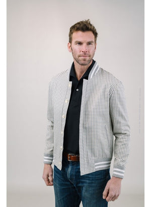 A man with light brown hair and a short beard wears the EDWARD ARMAH Pima Cotton Tailored Polo Shirt in dark blue and jeans, standing against a plain light background with a relaxed expression and one hand in his pocket.