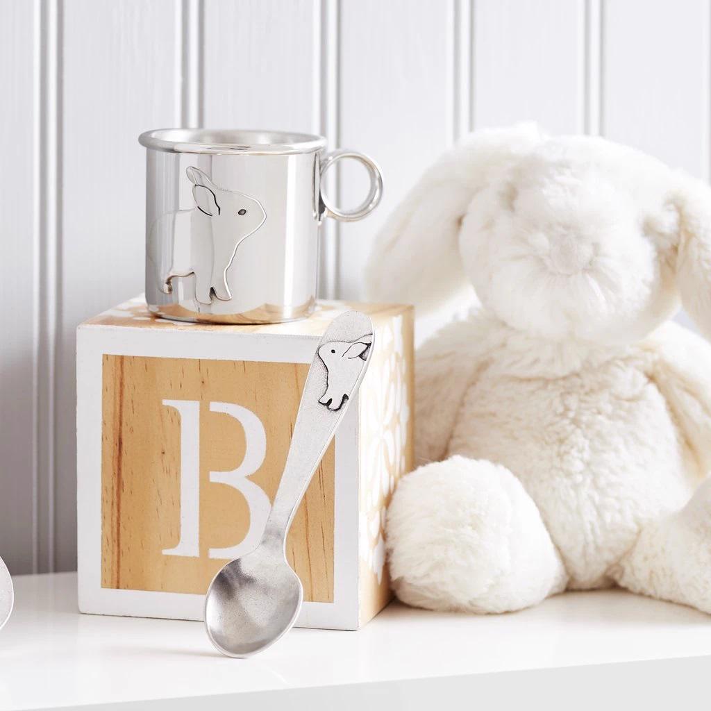 A plush white bunny sits beside a wooden block with the letter