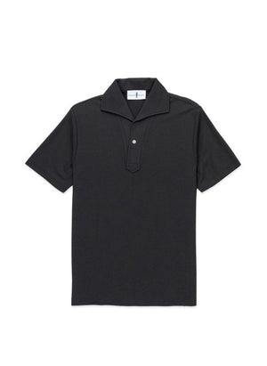 A man with light brown hair and a short beard wears the EDWARD ARMAH Pima Cotton Tailored Polo Shirt in dark blue and jeans, standing against a plain light background with a relaxed expression and one hand in his pocket.