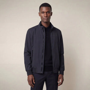 A man stands against a neutral background, wearing the SAVE THE DUCK - FINLAY JACKET IN BLUE BLACK with matching black shirt, trousers, and shoes. He has a neutral expression and his arms rest at his sides.