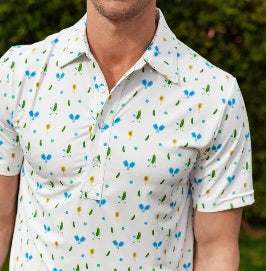 A man wears the CRIQUET Performance Sport Range Polo in white with a blue and yellow pickleballer print, standing against a plain background. This breathable men's polo is perfect for golf or any occasion.
