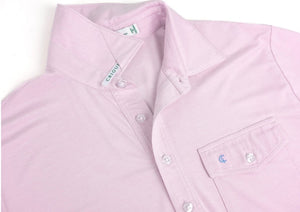 A man with a beard is wearing the CRIQUET Performance Sport Heather Players Shirt in Pink Panther and pale blue pants, standing against a plain white background.