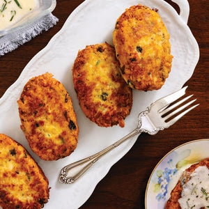 Person standing on a porch in front of a light blue house with a white door.