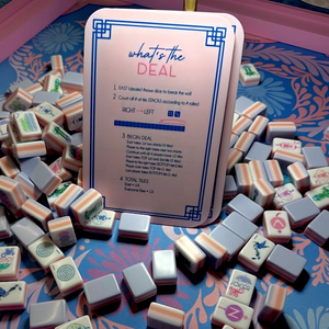 Mahjong tiles are arranged on a green table featuring the “FEARRINGTON VILLAGE” logo for MAHJONG NIGHT AT FEARRINGTON in the lower right corner. Various suits and honor tiles are neatly organized in rows and squares, reflecting the popular style of play enjoyed by participants from both Fearrington Village and Chapel Hill.