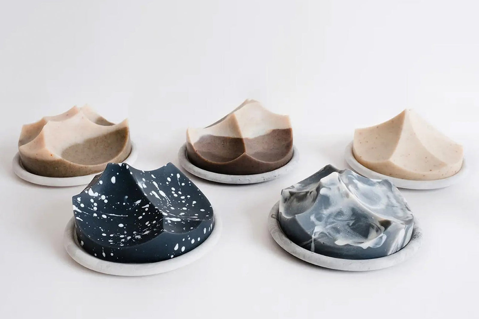 Five sculpted Ume Erode soaps in varying natural tones, each displayed on a small white dish.