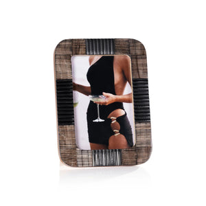 The ZODAX BLACK CHISELED HORN PHOTO FRAME 4X6 features a rectangular, textured design. Displayed is a photo of a woman in a black dress holding a wine glass, with her face not shown.