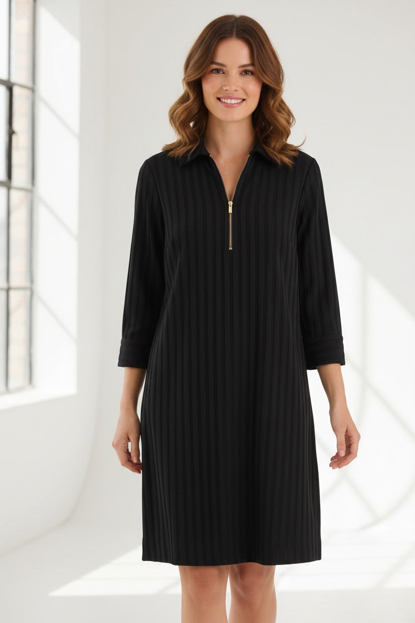 A woman with light brown hair and a slight smile stands against a light background, wearing the HINSON WU - Alessa 3/4 Sleeve Dress in Classic Stripe Black. This knee-length dress features vertical stripes, three-quarter sleeves, and a gold zip-up collar. Crafted from breathable fabric by HINSON WU, the look seamlessly blends style with comfort.