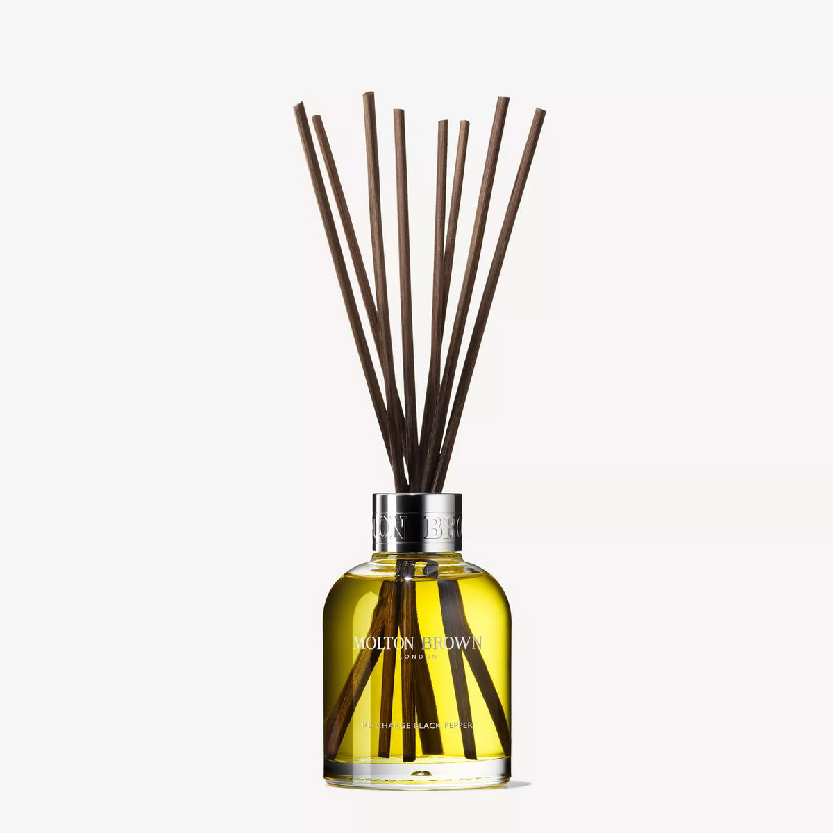 A yellow liquid in a glass bottle labeled &quot;MOLTON BROWN – RE-CHARGE BLACK PEPPER REED DIFFUSER&quot; holds dark reeds that diffuse a woody-citrus scent with vetiver notes throughout your home.