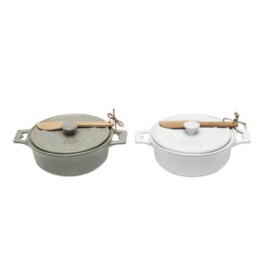 Set of two CREATIVE COOP stoneware brie bakers with lids—one gray, one white—each featuring handles and a matching wooden spreader tied on top.