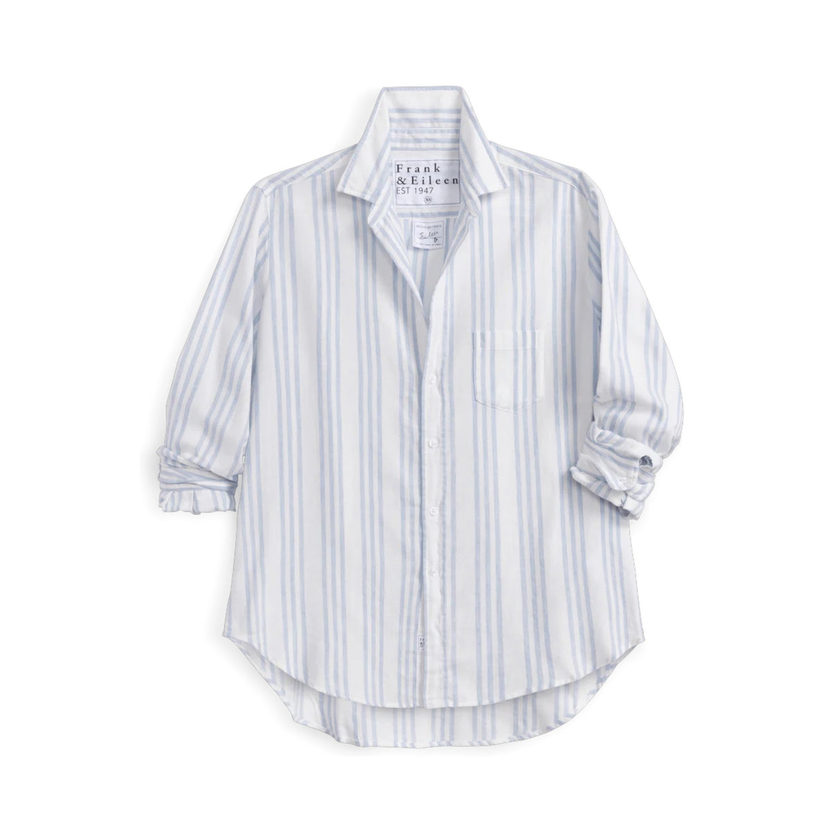 A woman smiles over her shoulder in a bright kitchen, wearing the FRANK &amp; EILEEN EILEEN Relaxed Button Up Shirt in Italian Flannel Blue Stripe, paired with blue jeans for an effortless, breezy look.