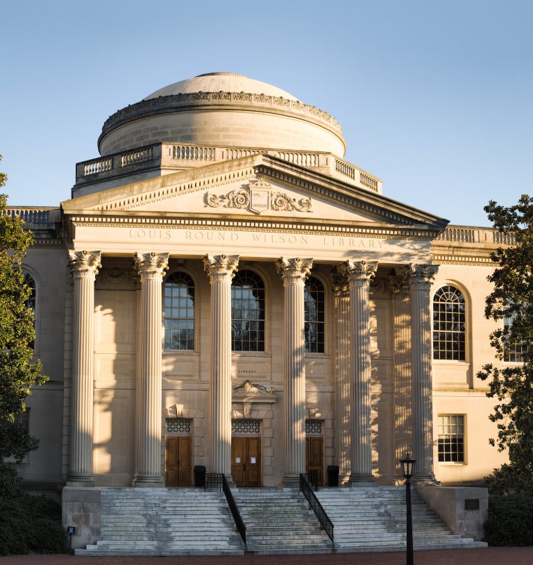 A neoclassical building with tall columns, arched windows, and a large dome. The inscription 