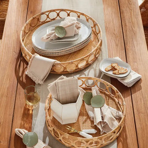 A close-up of the NAPA HOME AND GARDEN Ninette Rattan Round Tray, Small, in light brown with a woven base and decorative interlocking circular rim—ideal for boho decor—set against a plain white background.