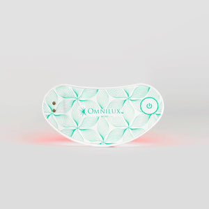 An individual relaxes with closed eyes, using the OMNILUX EYE BRIGHTNER KIT. The compact, curved device fits effortlessly under the eye, emitting red light therapy to target eye bags and enhance collagen production for a contented experience.
