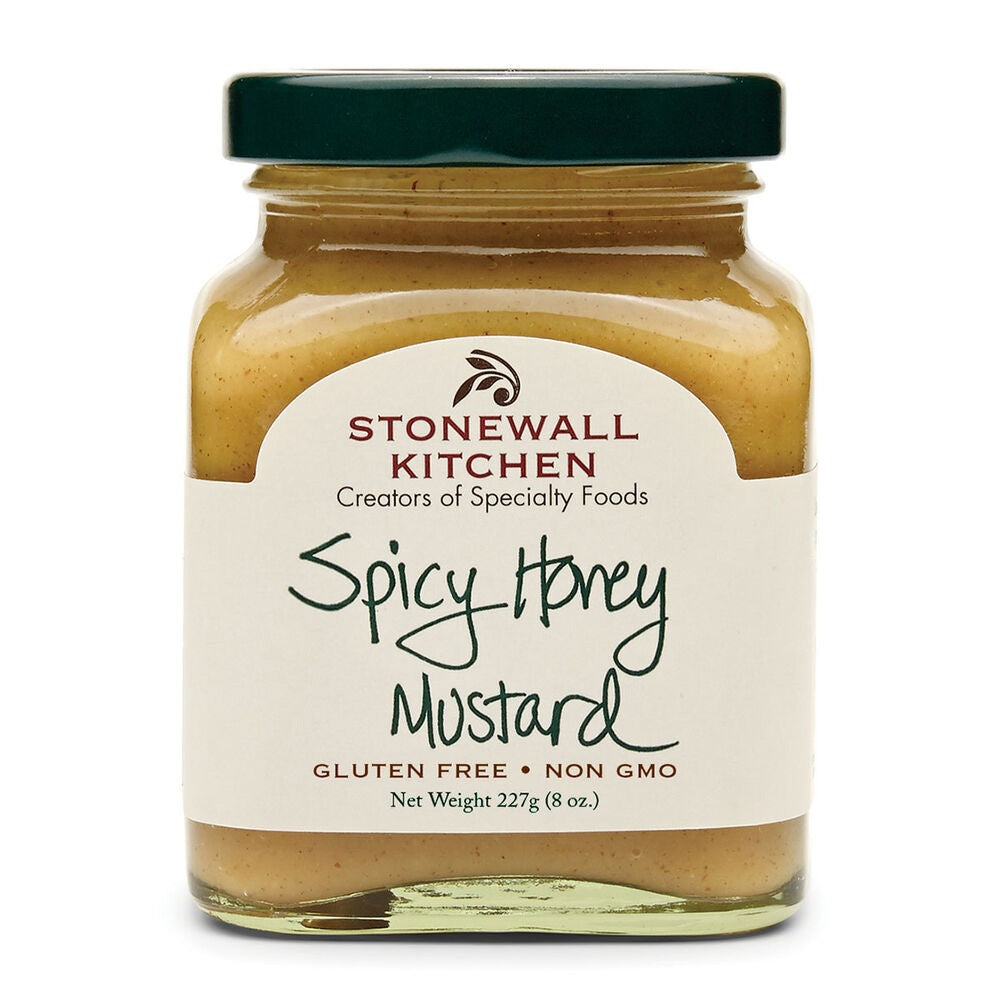 A jar of STONEWALL KITCHEN - SPICY HONEY MUSTARD sits on a slate board surrounded by puff pastry bites, accompanied by a bowl of this sweet and spicy mustard dipping sauce and wooden forks, all arranged on a woven placemat atop a wooden table.