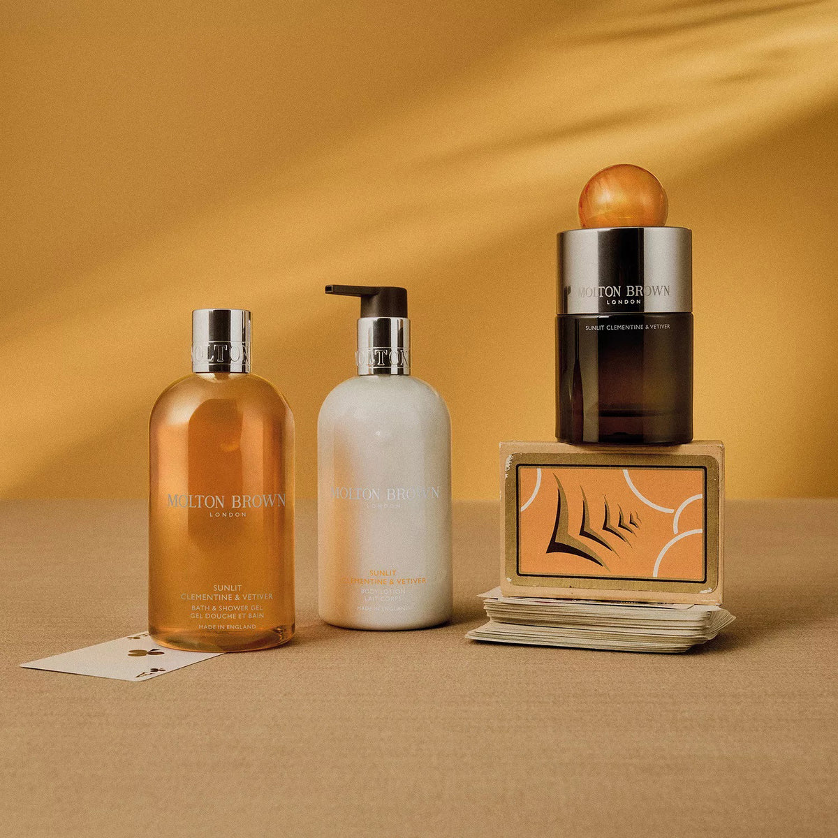 A black MOLTON BROWN SUNLIT CLEMENTINE &amp; VETIVER Eau de Parfum bottle with a large marbled orange cap hints at citrus and vetiver notes, set against a plain white background.