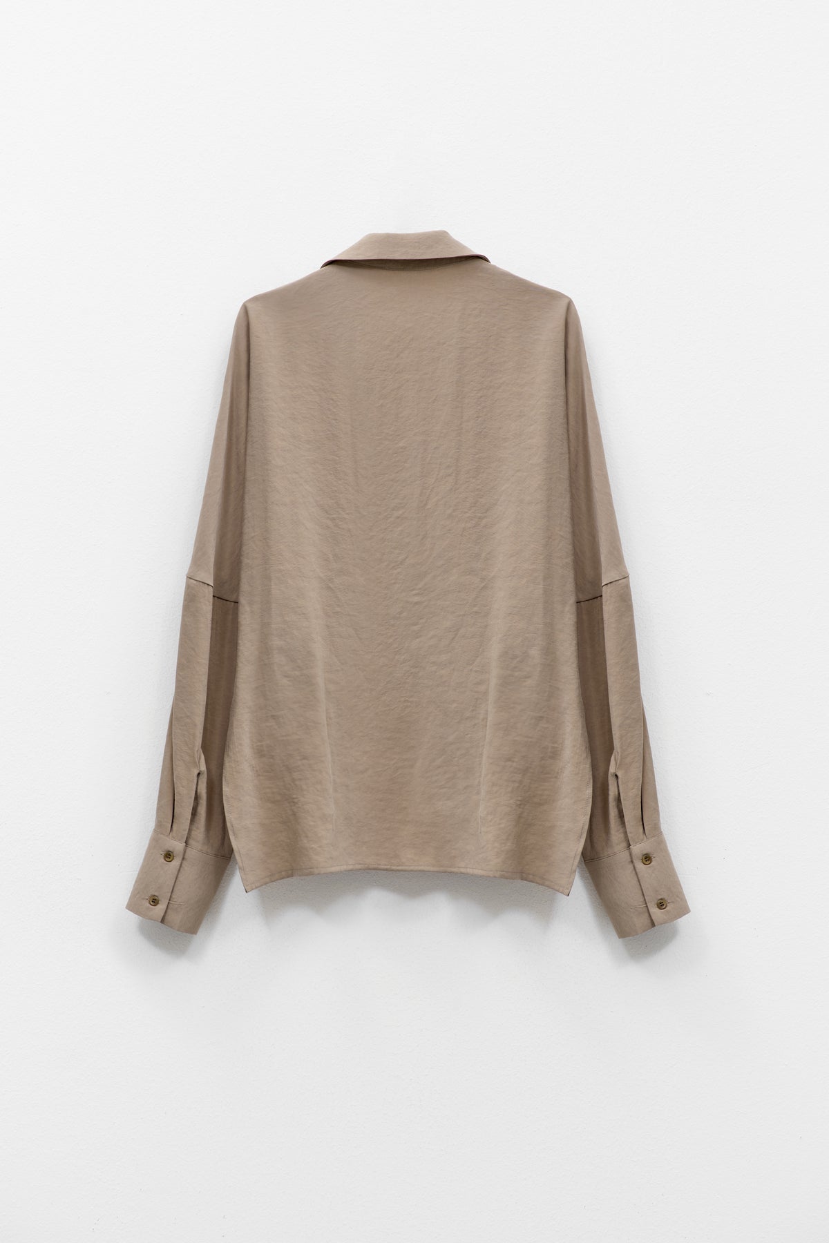 The ELEH - DRAPE FRONT BLOUSE by ELEH is a taupe Italian cotton top with a draped crossover front, wide cuffs, and a loose fit, shown against a plain white background.