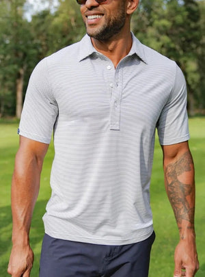 A smiling man with short hair and a beard wears the CRIQUET - Performance Sport Range Polo in Hobby Stripe - Gray as he holds a canned drink in a green koozie, facing slightly to the left against a plain white background.