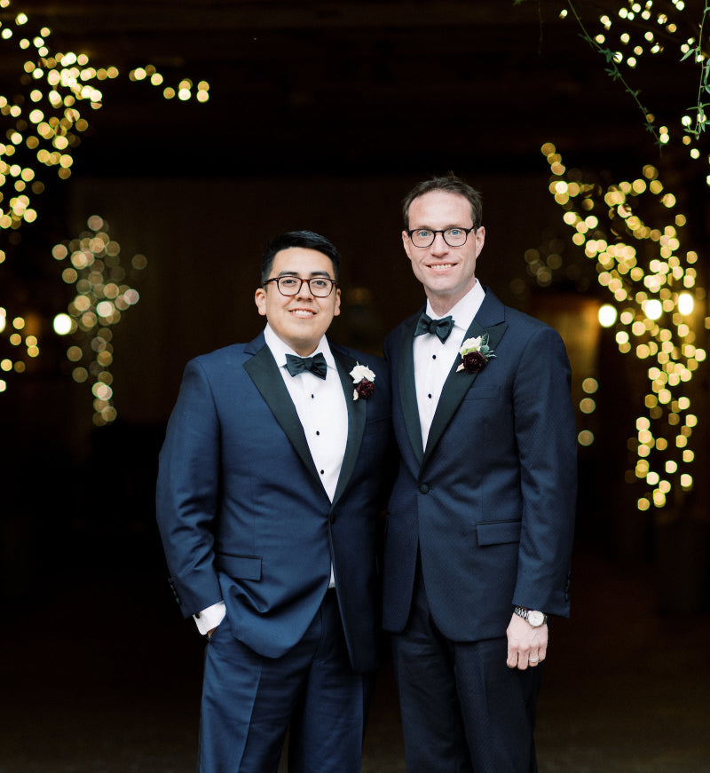 Two men in suits standing in front of a decorative light archway.