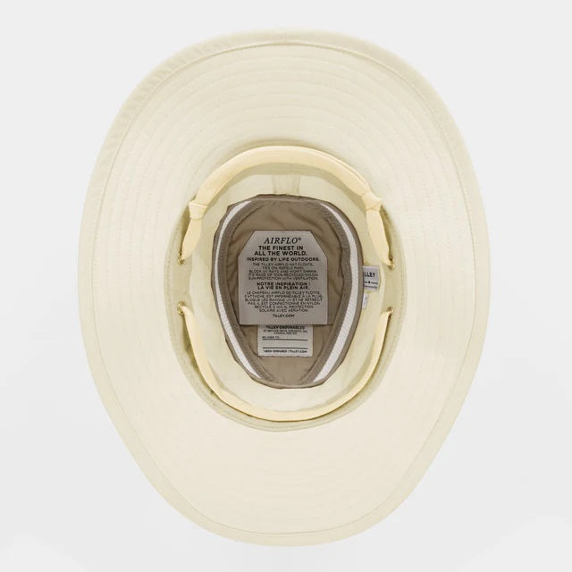 The TILLEY AIRFLO BROAD BRIM HAT LTM6 in Light Stone is a recycled nylon sun hat with UPF 50+ protection, wide brim, mesh ventilation near the crown, and a small band tag. Shown on a plain white background.