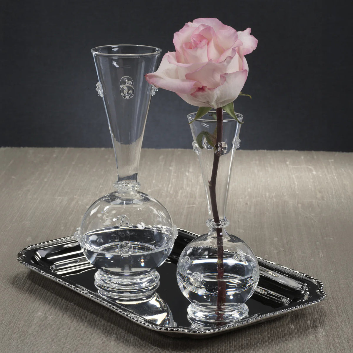 The VENDOME GLASS VASE - SMALL by ZODAX features a clear round base, tall narrow neck with decorative glass dots, stands on a circular foot, and measures 3 in x 7.75 in (7.62 cm x 19.69 cm).
