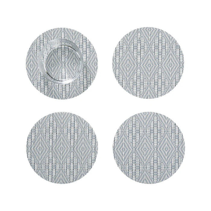 The CHILEWICH - BOXWOOD BACKED COASTER SET4 features four round coasters with a subtle gray diamond pattern and lace-like weave. Arranged in a square on a white background, the top left coaster holds a clear glass.