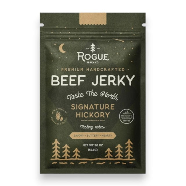 A dark green pouch of ROGUE JERKY - HICKORY BEEF JERKY by ROGUE JERKY CO., featuring forest and moon imagery, labeled “Premium Handcrafted” and “Taste The North.” This savory, buttery, hearty sugar free jerky is an ideal keto friendly snack. Net weight: 2 oz.
