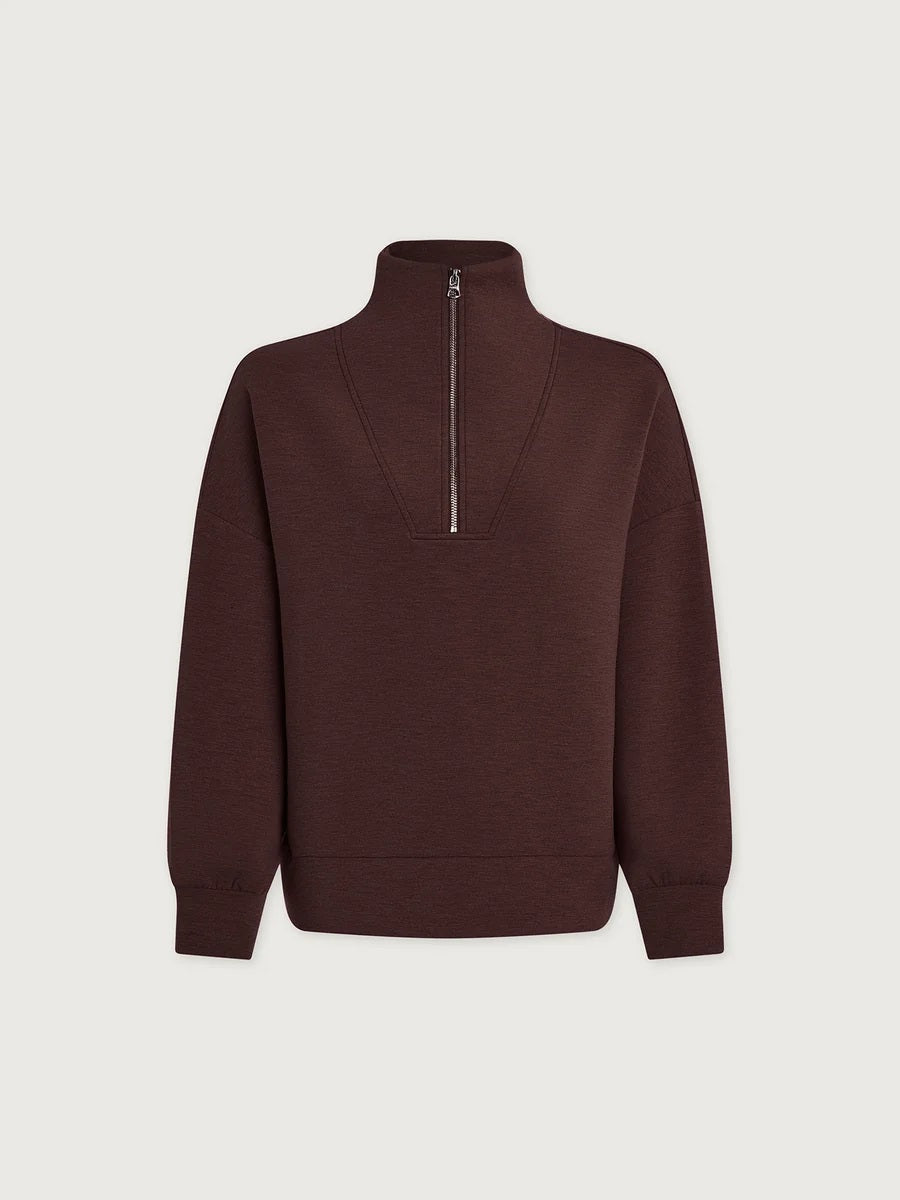 A person wears an oversized, dark brown VARLEY - HAWLEY HALF-ZIP SWEATSHIRT IN COFFEE BEAN MARL with a gold zipper.