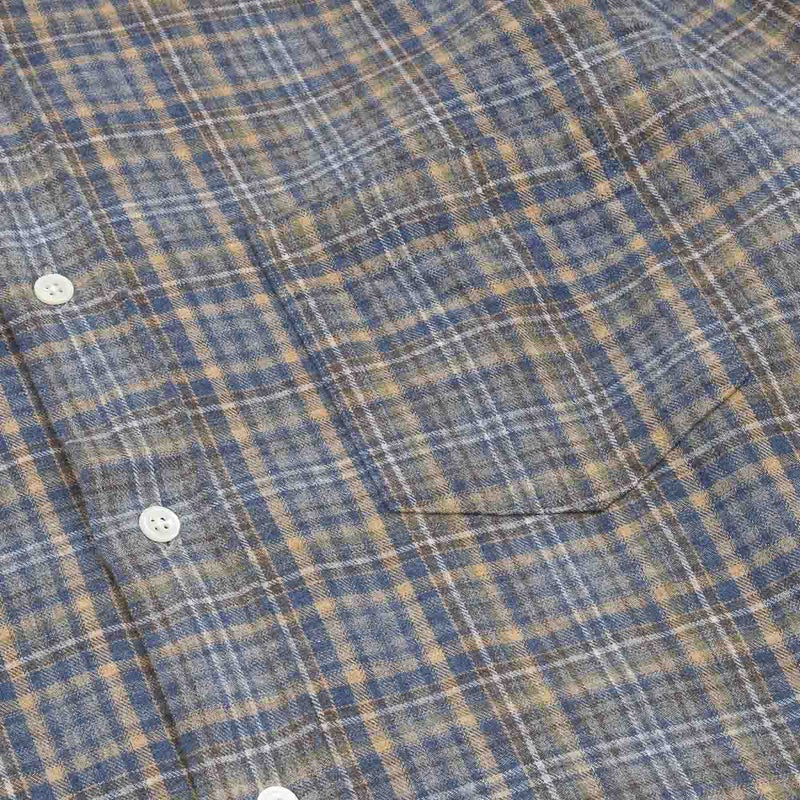 A close-up of the HARTFORD - PAUL Checked Flannel Shirt in Grey highlights the blue, brown, and grey plaid cotton fabric, with a focus on the cuff and sleeve featuring visible white buttons.
