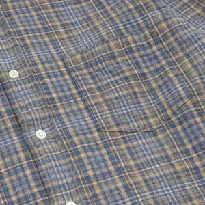 A close-up of the HARTFORD - PAUL Checked Flannel Shirt in Grey highlights the blue, brown, and grey plaid cotton fabric, with a focus on the cuff and sleeve featuring visible white buttons.