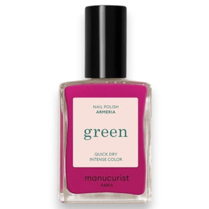 A close-up of MANUCURIST - GREEN™ NAIL POLISH IN ARMERIA by MANUCURIST INC being spread with a brush on a smooth surface, showcasing its vibrant pinky mauve shade, glossy texture, and distinctive curved brushstroke.