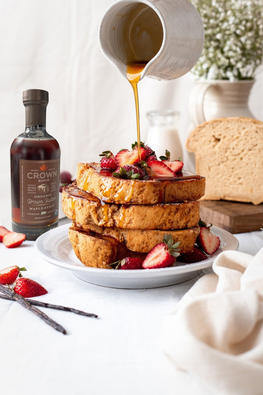 A bottle of CROWN MAPLE - BROWN BUTTER ORGANIC MAPLE SYRUP from the CROWN MAPLE brand, featuring a brown label with a gold cap, product details, and an organic certification badge.