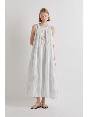 A person stands against a plain white background, wearing the MEIMEIJ Sleeveless Maxi Dress with Stripes, an ankle-length summer piece styled with flat sandals and a statement necklace for an effortlessly chic look.
