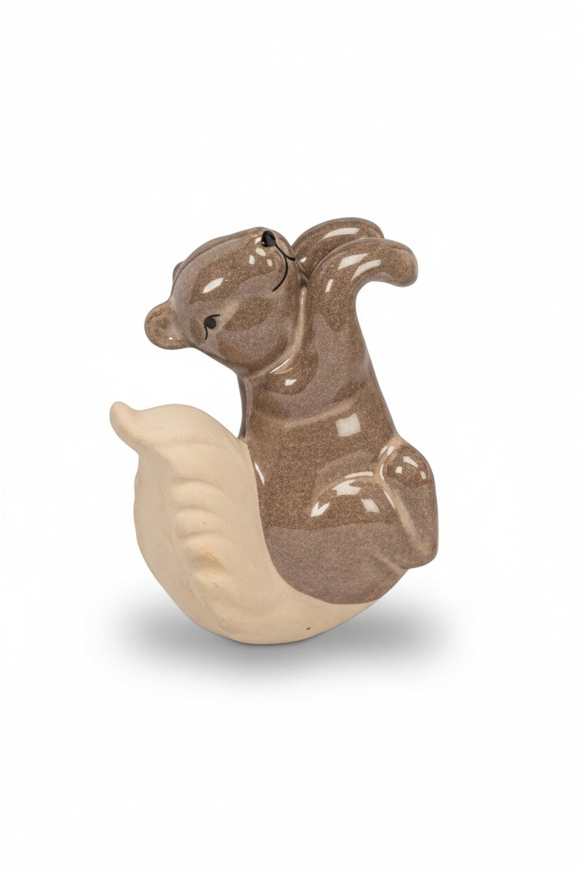 A brown ceramic CLIMBING SQUIRREL POT HANGER by ABBOTT perched on the rim of a planter.