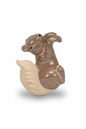 A brown ceramic CLIMBING SQUIRREL POT HANGER by ABBOTT perched on the rim of a planter.