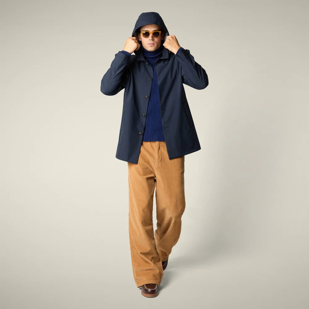 The SAVE THE DUCK - BENJAMIN Hooded Raincoat in Blue Black is a men's lightweight waterproof jacket made from recycled polyester, featuring a button-down front and classic design. Displayed on a plain light beige background.