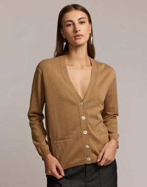 A woman with straight brown hair wears the HINSON WU CASSIE Long Sleeve Cotton Silk Cardigan in camel, styled with black pants. She poses confidently, one hand to her chin, against a neutral backdrop.