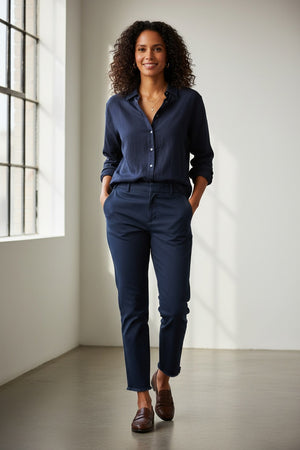 A pair of FRANK & EILEEN’s THE WICKLOW Italian Chinos in Performance Twill, featuring a navy blue color, straight legs, and raw unfinished hems, is laid flat on a light textured background for an Italy-meets-California vibe.