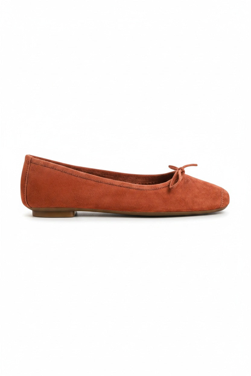 The REQINS - HARMONY Suede Ballerina Flat in Brique is shown in soft suede goatskin with a small bow on the toe, displayed side view against a plain white background.