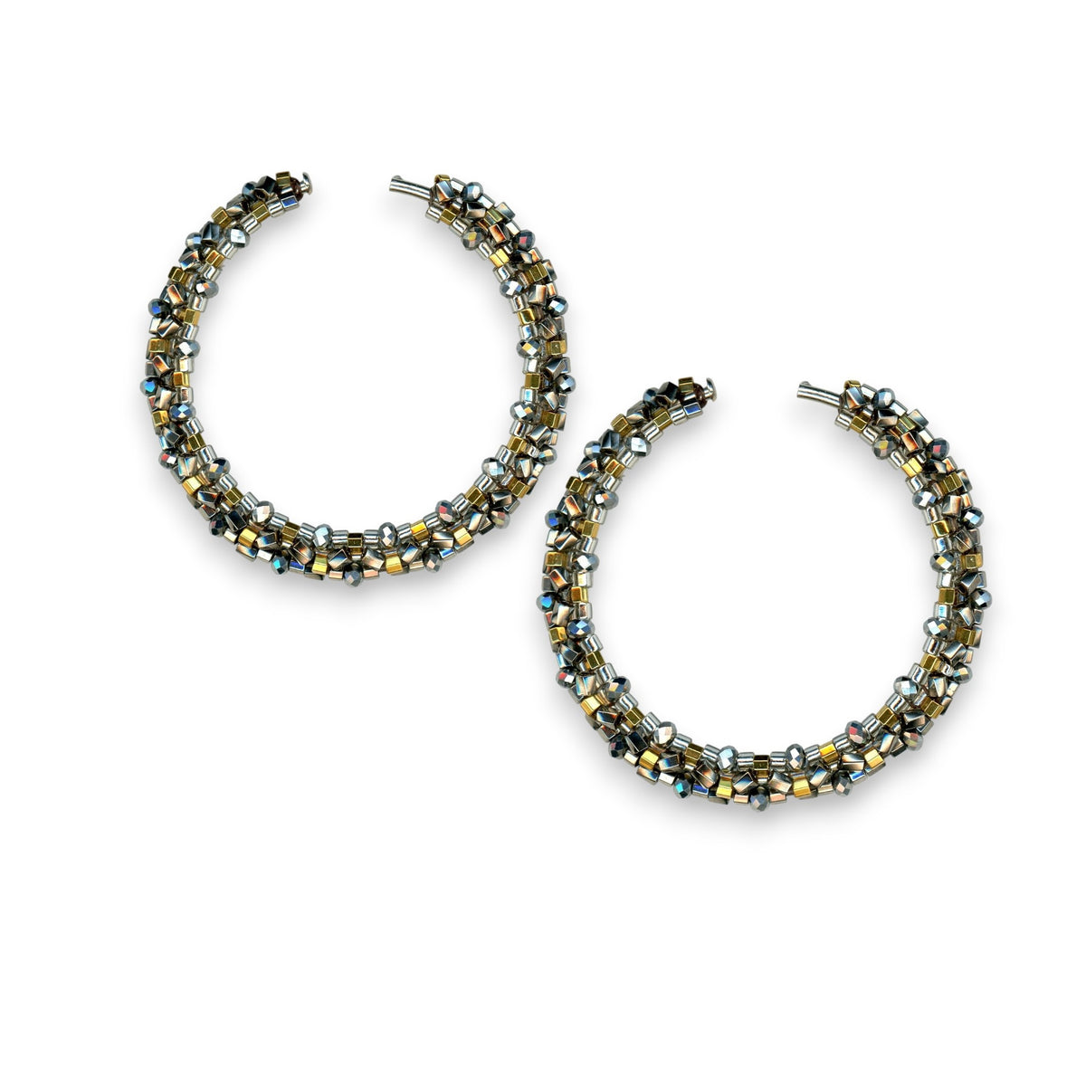 Close-up of two textured MIGUEL ASES - Miyuki crystal bead pyrite earrings on a white background. Crafted by MIGUEL ASES, INC., they feature small Miyuki crystal beads in gold, silver, and black, creating a shimmering effect with a handwoven technique.