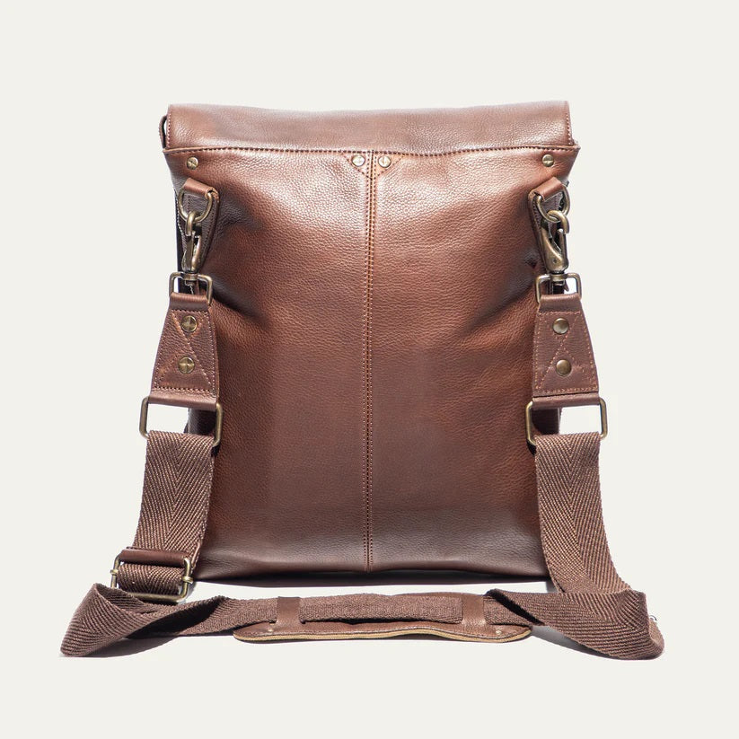 The WILL LEATHER GOODS - OTTO CROSSBODY BAG IN COGNAC, a full-grain leather bag with plaid lining, is shown open from above holding a camera, book, and wallet.