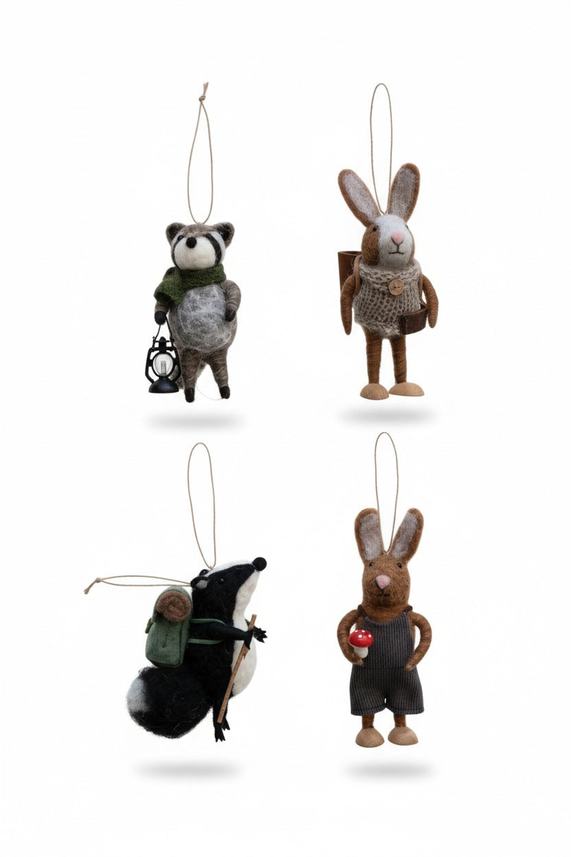 Four HANDMADE FELT FOREST ANIMAL ORNAMENTS depicting a raccoon with a lantern, a rabbit with a backpack, a badger with a hiking pack and staff, and a rabbit holding a mushroom.